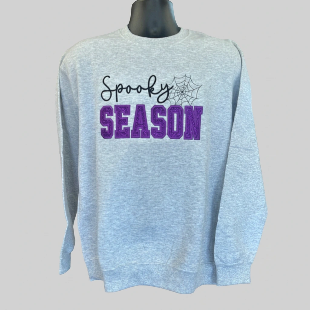 Gray Spooky Season crewneck sweatshirt with purple lettering on a neutral background