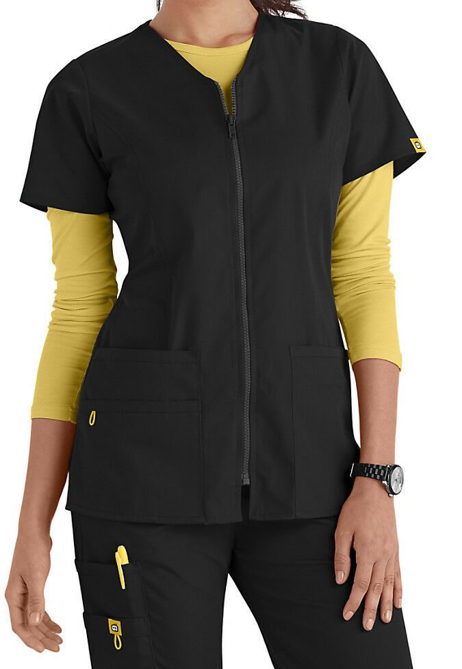 Model wearing a black WonderWink scrub top over a yellow long sleeve tee
