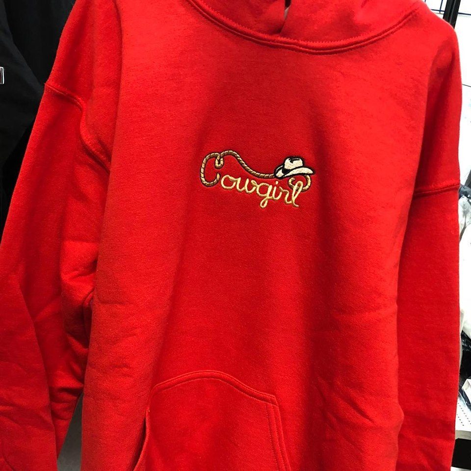 Red hoodie with a Cowgirl script and boot design embroidered on the chest